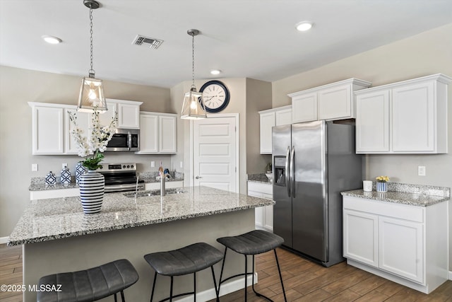 kitchen with stainless steel appliances, visible vents, a sink, and dark wood finished floors