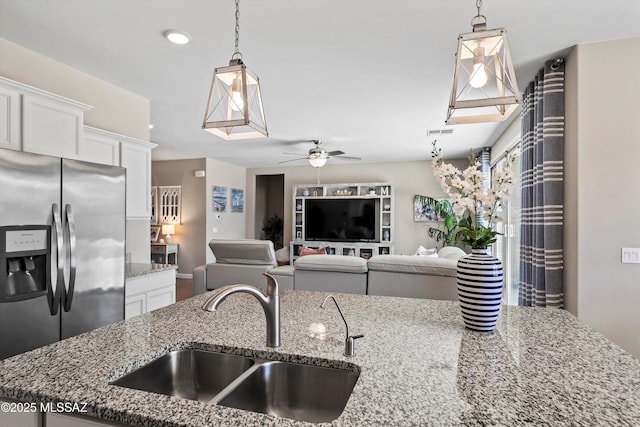 kitchen featuring stone counters, a ceiling fan, a sink, and stainless steel fridge with ice dispenser