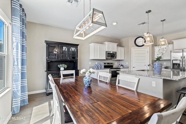dining area featuring baseboards, light wood-style floors, visible vents, and recessed lighting