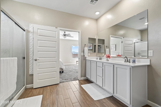 bathroom with a stall shower, wood finished floors, visible vents, and a sink