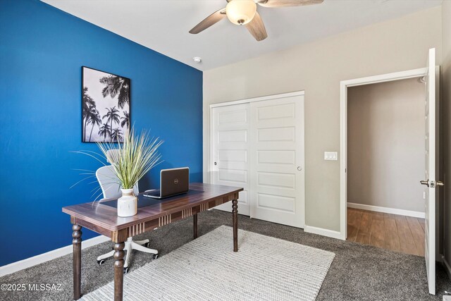 carpeted office space with baseboards and a ceiling fan