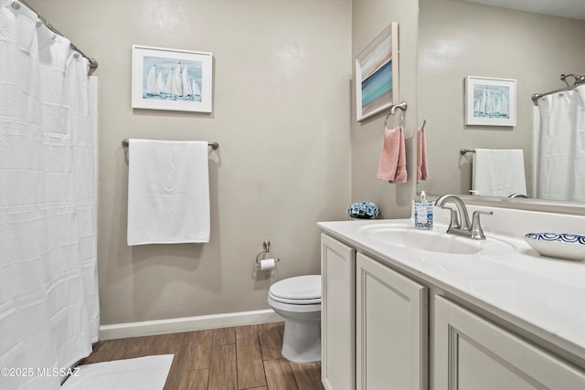 bathroom featuring baseboards, wood finished floors, vanity, and toilet