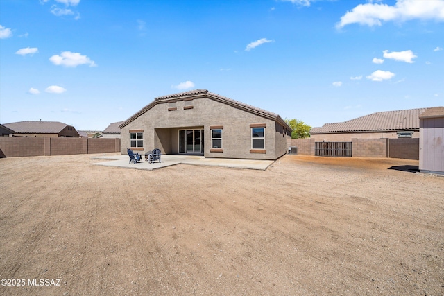 rear view of house with stucco siding, a tile roof, a patio area, and a fenced backyard