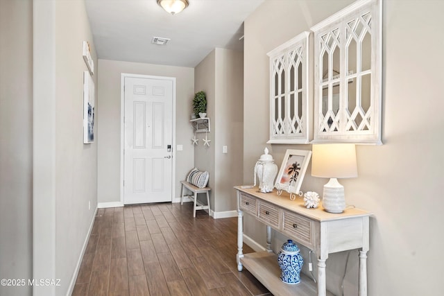 interior space featuring baseboards, visible vents, and dark wood-style floors