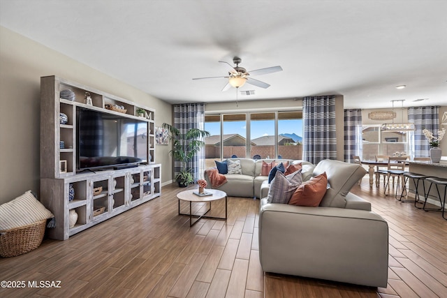 living room with visible vents, baseboards, a ceiling fan, and wood finished floors