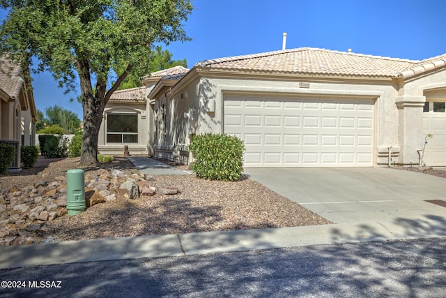 view of front of house with a tiled roof, driveway, a garage, and stucco siding