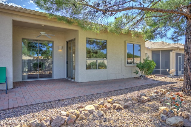 back of property with a sunroom, a patio area, ceiling fan, a tile roof, and stucco siding