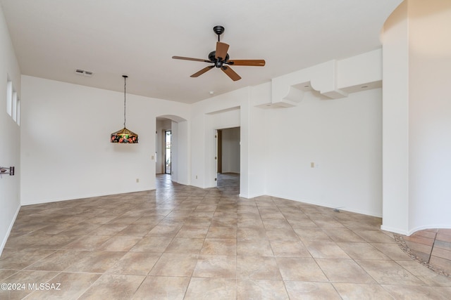 spare room with arched walkways, visible vents, baseboards, and ceiling fan