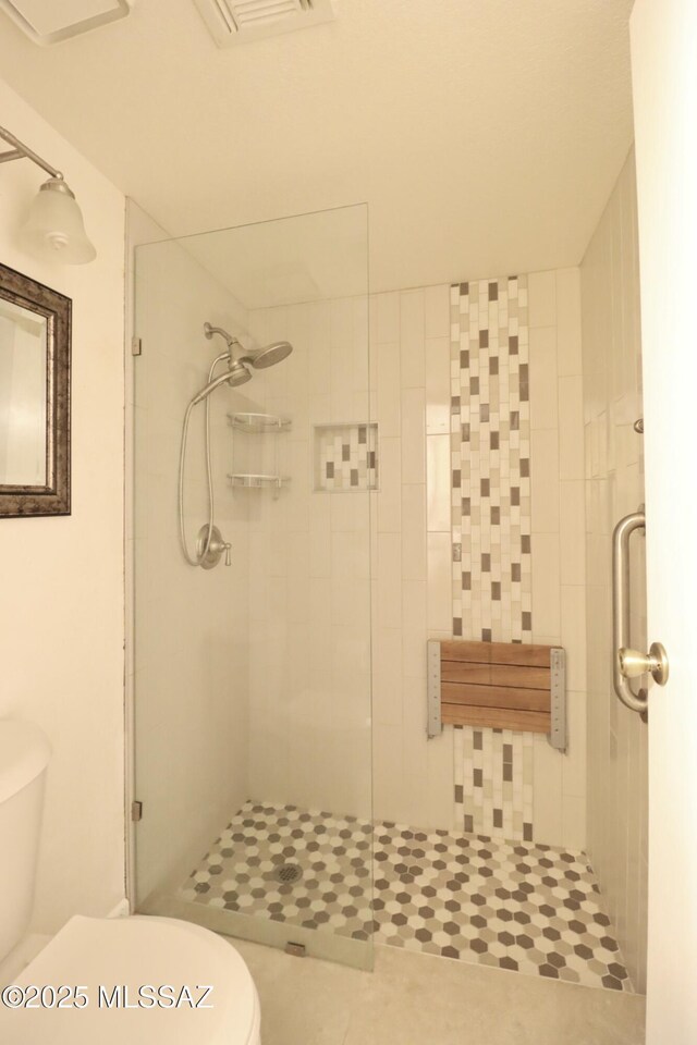 full bathroom with toilet, a stall shower, and visible vents