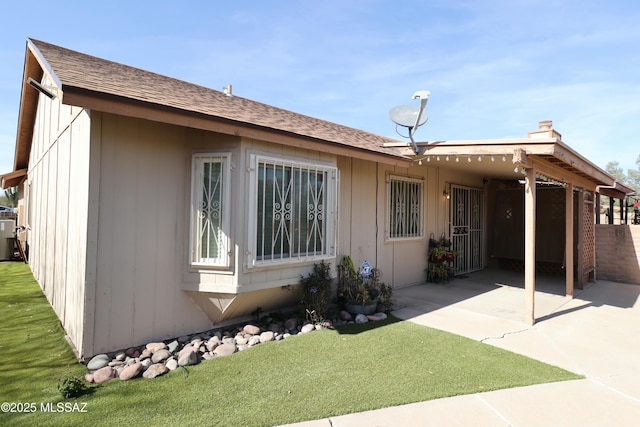 exterior space featuring a patio, a yard, and a shingled roof