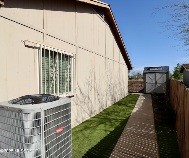 view of side of home featuring an outdoor structure, a storage shed, cooling unit, and fence