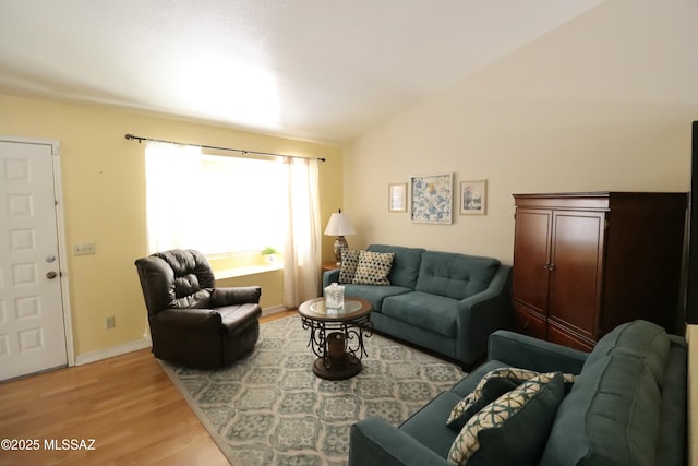 living room featuring light wood-style floors, baseboards, and vaulted ceiling
