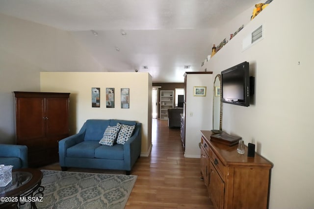 living area featuring baseboards, vaulted ceiling, and wood finished floors