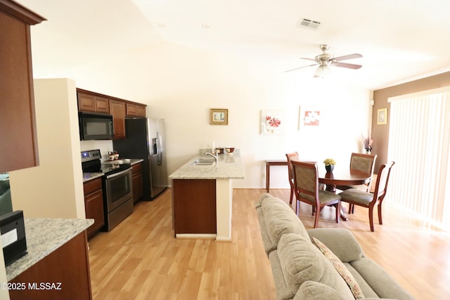 kitchen featuring a peninsula, a ceiling fan, light wood-style floors, appliances with stainless steel finishes, and a sink