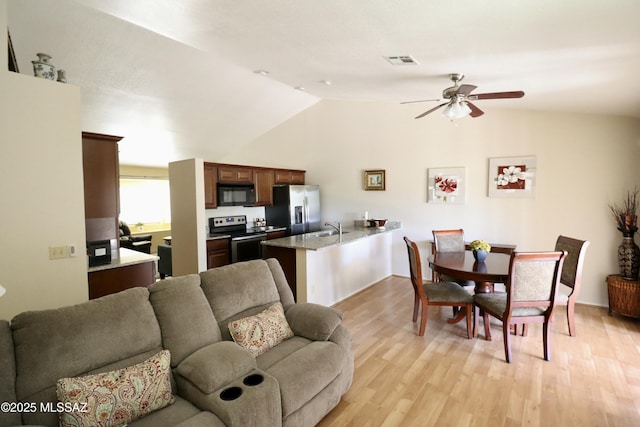 living room with visible vents, ceiling fan, light wood finished floors, and vaulted ceiling