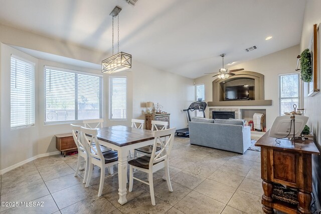 dining space featuring a ceiling fan, visible vents, a fireplace, light tile patterned floors, and lofted ceiling