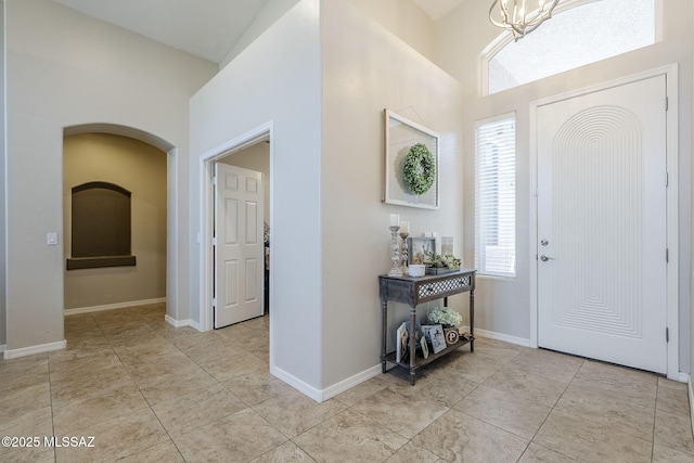 entryway featuring light tile patterned floors, arched walkways, and an inviting chandelier