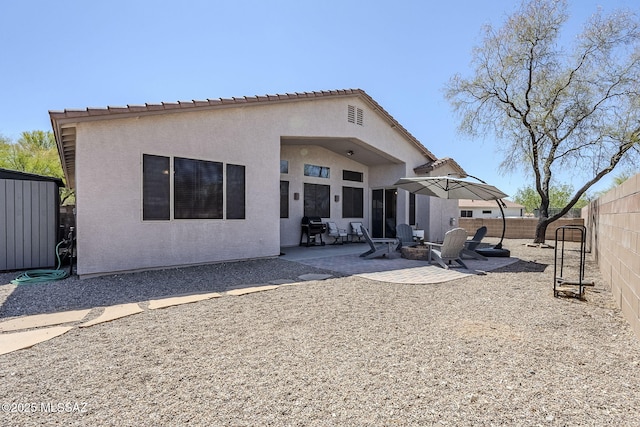 rear view of house with a fenced backyard, a patio area, and stucco siding