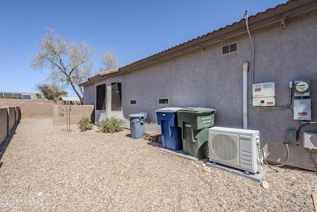 back of property with a fenced backyard, ac unit, stucco siding, and a tiled roof
