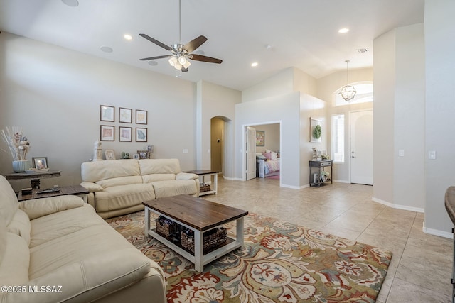 living area with ceiling fan, a towering ceiling, arched walkways, light tile patterned floors, and recessed lighting