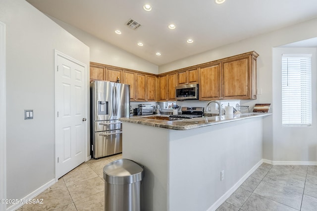 kitchen with vaulted ceiling, brown cabinets, baseboards, stainless steel appliances, and recessed lighting