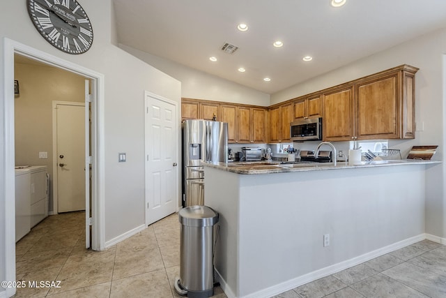 kitchen with brown cabinetry, independent washer and dryer, visible vents, appliances with stainless steel finishes, and stone countertops