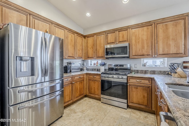 kitchen with brown cabinetry, light tile patterned floors, and stainless steel appliances