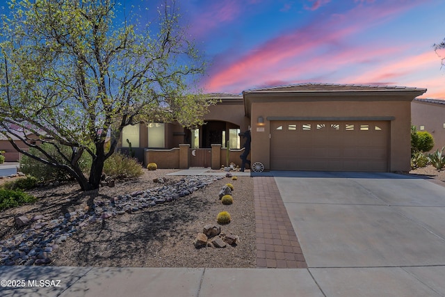 view of front facade featuring a garage, driveway, stucco siding, and a tiled roof