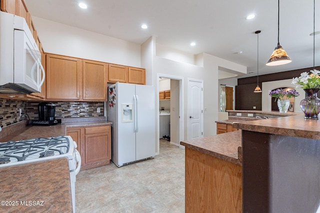 kitchen with white appliances, washer / dryer, dark countertops, hanging light fixtures, and backsplash