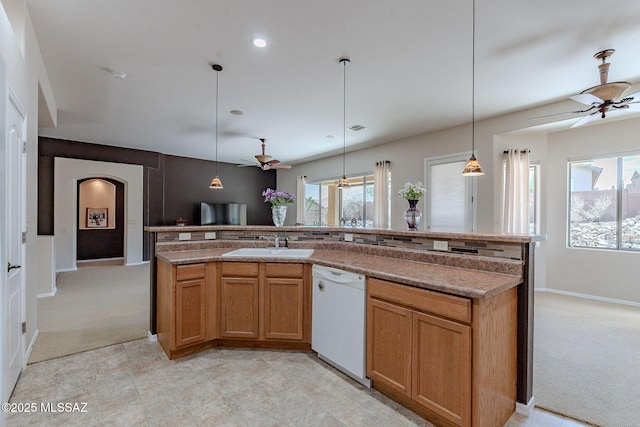 kitchen featuring light colored carpet, dishwasher, a ceiling fan, and arched walkways