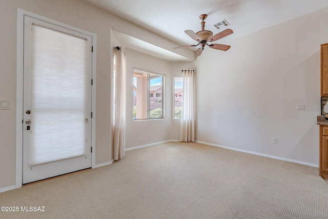 interior space featuring visible vents, light colored carpet, baseboards, and ceiling fan