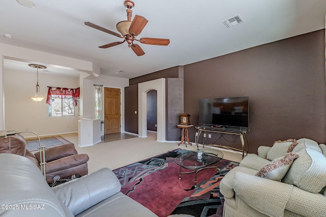 living area featuring carpet, baseboards, a ceiling fan, and visible vents