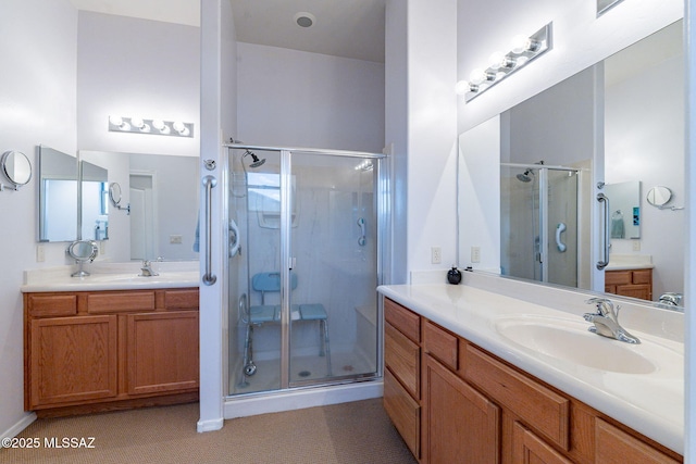 full bath featuring a sink, two vanities, and a stall shower