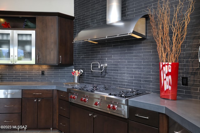 kitchen with stainless steel gas stovetop, tasteful backsplash, dark brown cabinetry, and wall chimney exhaust hood