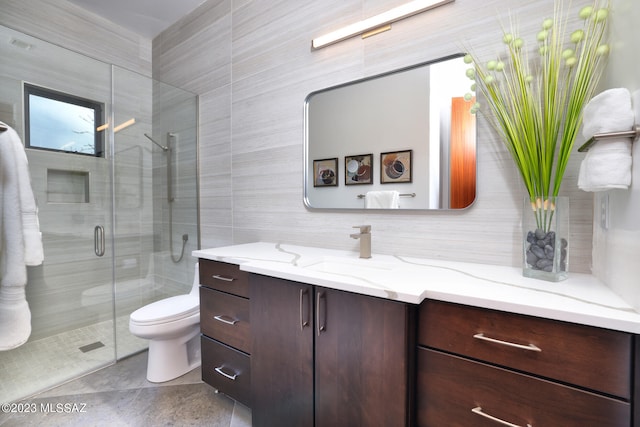bathroom with vanity, a stall shower, toilet, and tile walls