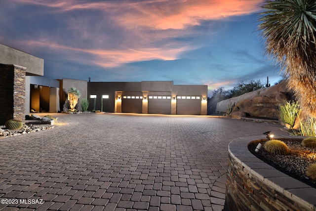 view of front of property with decorative driveway, a garage, and stucco siding