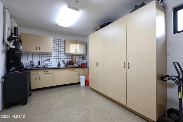kitchen with light brown cabinetry, backsplash, and dark countertops