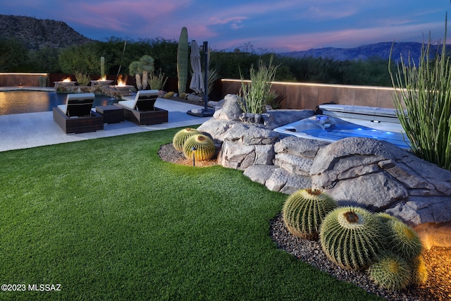 yard at dusk featuring a mountain view, a fire pit, and a patio