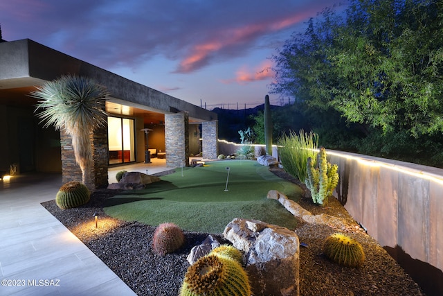 yard at dusk featuring fence and a patio area
