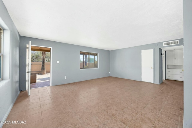 unfurnished living room featuring light tile patterned floors, visible vents, and baseboards