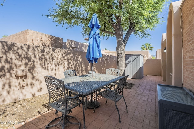 6120 E 5th St Unit B121, Tucson, AZ 85711 - view of patio featuring a fenced backyard, outdoor dining space, a storage unit, and an outdoor structure