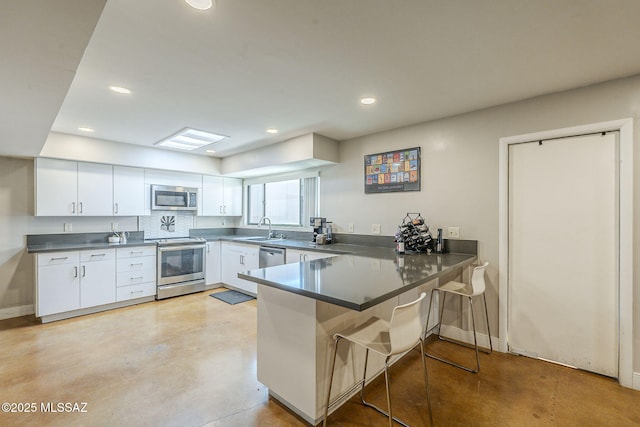 6120 E 5th St Unit B121, Tucson, AZ 85711 - kitchen featuring appliances with stainless steel finishes, a sink, a peninsula, a breakfast bar area, and white cabinets