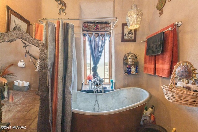 bathroom featuring a soaking tub and stone finish flooring