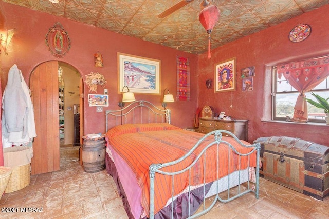bedroom featuring stone finish flooring, arched walkways, and an ornate ceiling