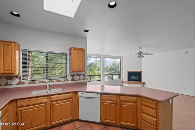 kitchen with a peninsula, tasteful backsplash, a sink, white dishwasher, and open floor plan