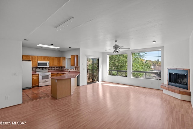 kitchen featuring tasteful backsplash, white appliances, light wood-style flooring, and open floor plan