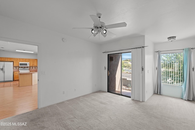 empty room with ceiling fan, plenty of natural light, and light carpet