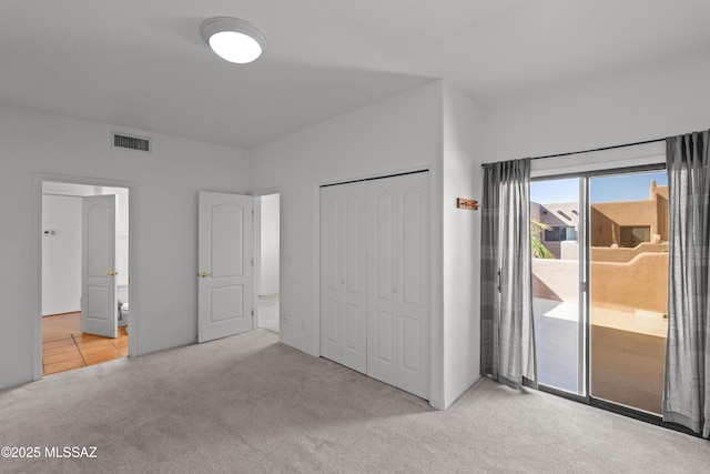 unfurnished bedroom with carpet, access to outside, a closet, and visible vents