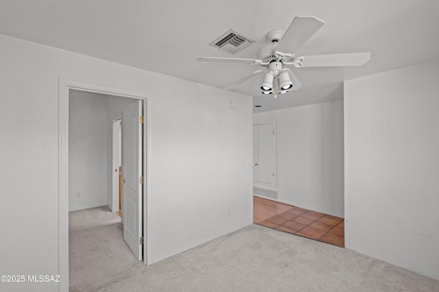carpeted spare room with visible vents and ceiling fan