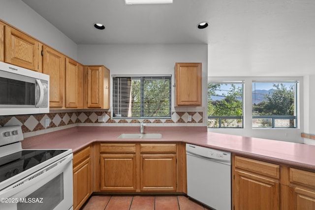 kitchen featuring tasteful backsplash, white appliances, light tile patterned floors, light countertops, and a sink